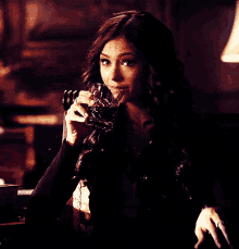 a woman is holding a glass of wine in her right hand