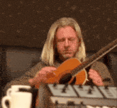 a man playing an acoustic guitar with his eyes closed