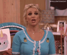 britney spears is holding a picture of a unicorn cake .