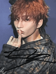 a young man with red hair has his finger to his mouth