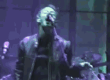 a man singing into a microphone while playing drums