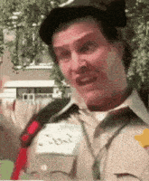 a man in a scout uniform is making a funny face while wearing a name tag .