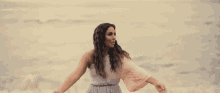 a woman with her arms outstretched stands on a beach