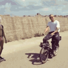 a man riding a bicycle next to a man on a skateboard