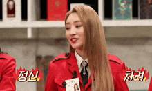 a woman in a red suit and tie is standing in front of a shelf with chinese writing on it .