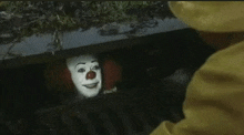 a close up of a clown coming out of a hole in the ground .