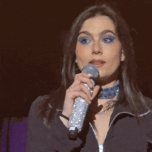 a woman in a black jacket is holding a microphone