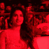 a woman in a red dress is sitting in front of a crowd of people .