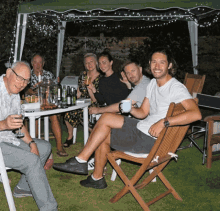 a group of people are sitting around a table with drinks