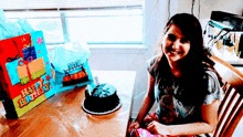 a girl sits at a table with a birthday cake and a bag that says happy birthday