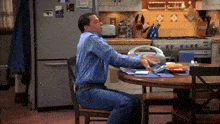 a man is sitting at a table in a kitchen with a sticker on the refrigerator that says ' i love you '