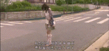 a woman is standing in the middle of a street with foreign writing on the bottom of the screen .