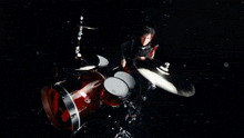 a man is playing drums in a dark room with a red light behind him