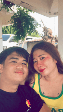a man and a woman are posing for a picture and the woman is wearing a yellow tank top that says a8 on it