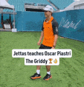 a man in an orange shirt stands in front of a miami banner