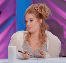 a woman in a white fur coat is holding a pen