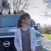 a woman stands in front of a nissan vehicle