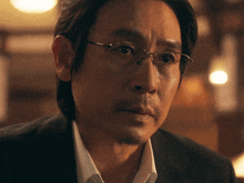 a man wearing glasses and a suit looks serious