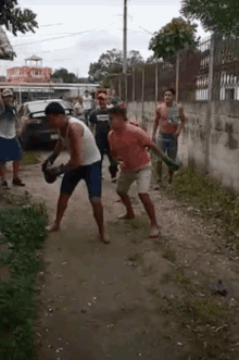 a group of men are standing on a dirt road fighting one another .