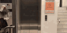 a man with a beard is standing in an elevator next to a sign for northern skin and laser