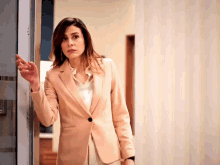 a woman in a suit is standing in a hallway