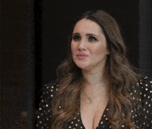 a woman wearing a black and gold polka dot dress is making a sad face