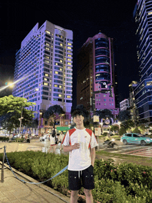 a young man stands in front of a large building that says ' a ' on it