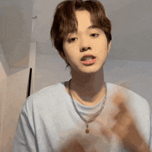 a young man wearing a white shirt and a necklace
