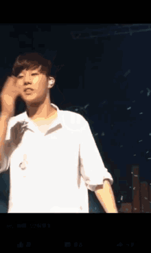 a young man in a white shirt is standing in front of a microphone