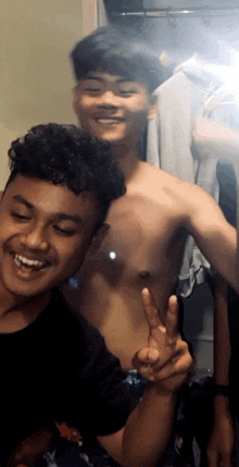 two young men are posing for a picture in front of a mirror and one of them is shirtless
