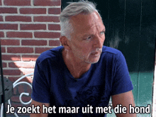 a man in a blue shirt with the words je zoekt het maar uit met die hond written below him