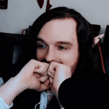 a man with long hair and a beard is making a funny face with his hands .