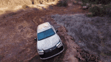 a white lexus suv is driving through a dirt road
