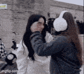 two women wearing ear muffs are standing next to each other