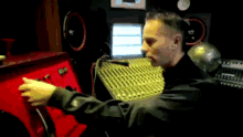 a man in a black jacket is sitting in front of a red box that says ' a ' on it