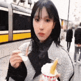 a woman is eating an ice cream cone on the street .