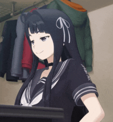 a girl with long black hair is standing in front of a rack of clothes