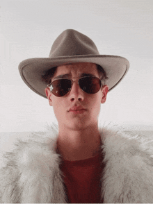 a man wearing a hat and sunglasses has a fur coat on