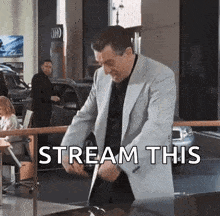 a man in a suit is standing in front of a car with the words stream this written above him