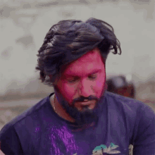 a man with a beard and a purple shirt has pink paint on his face