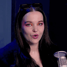 a woman with sunglasses on her head stands in front of a microphone with her mouth open