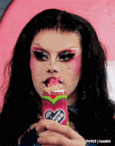 a drag queen is drinking from a pink can with a heart on the front