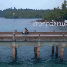 a couple riding a motorcycle on a bridge with a sign in the background that says ' a ' on it