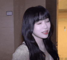 a woman with long black hair is standing in a room with her eyes closed and her tongue hanging out .