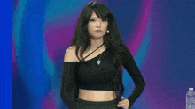 a woman in a black crop top is standing in front of a microphone and a bottle of water .