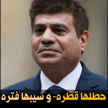 a man in a suit and tie with arabic writing on the bottom right