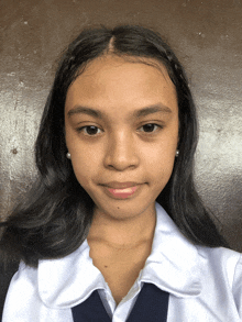 a young girl in a school uniform looks at the camera with a serious look on her face