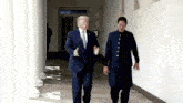a man in a suit and tie is walking down a hallway with another man .