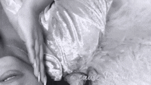 a black and white photo of a woman laying on a bed .