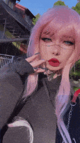 a woman with pink hair is wearing a black shirt